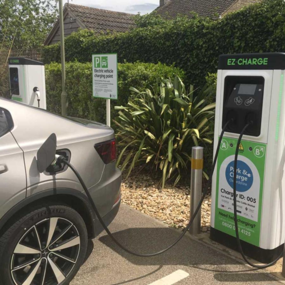 Electric car plugged into a Park and Charge Oxfordshire charging point labelled “EZ Charge” in a residential roadside setting.